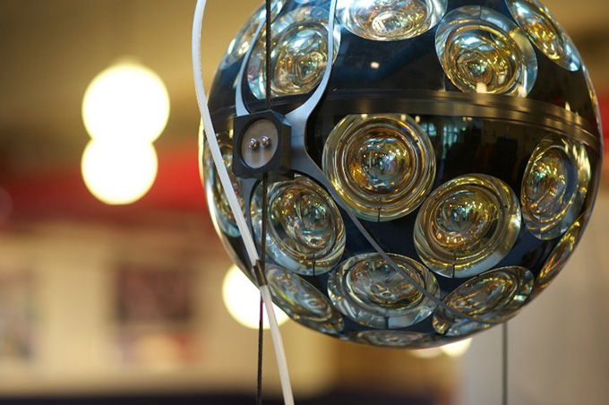 An orb of machinery covered in glimmering glasslike circles is shown up close