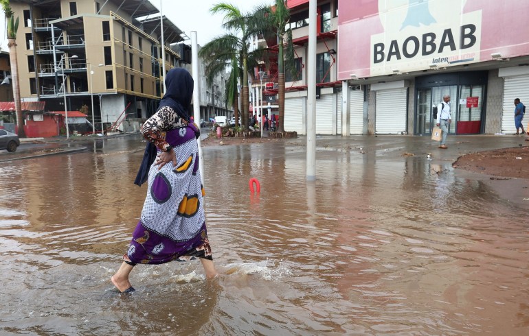 A person walks in a flooded street after heavy rains in the aftermath of Cyclone Chido, in Mamoudzou, Mayotte, France, December 19, 2024.