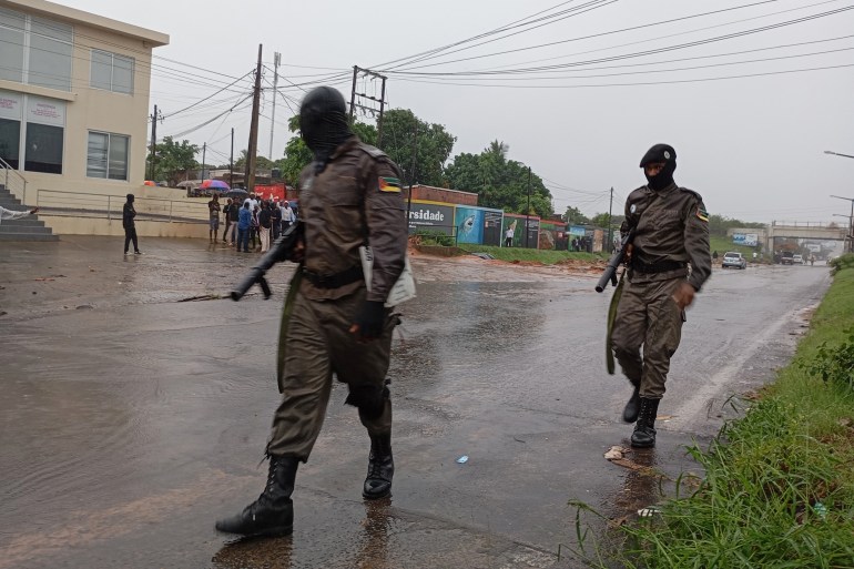 Mozambique police officers walk in a street near a checkpoint near the airport in Maputo on January 9, 2025. Mozambique's opposition leader is expected to return from exile on January 9, 2025 to push his claim to have won presidential elections, risking an escalation in a dispute about the vote just days ahead of the swearing in of his rival. (Photo by Amilton Neves / AFP)