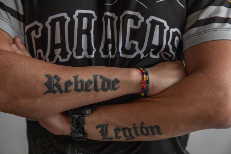 Jesus Medina crosses his arms, two tattoos stretching on the outside of his forearms: "Rebelde" and "Legion"