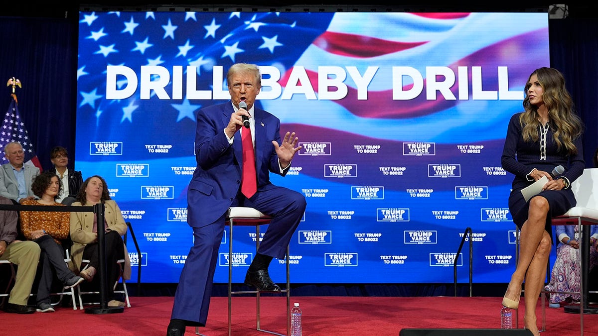 Trump sits in front of Drill Baby Drill sign