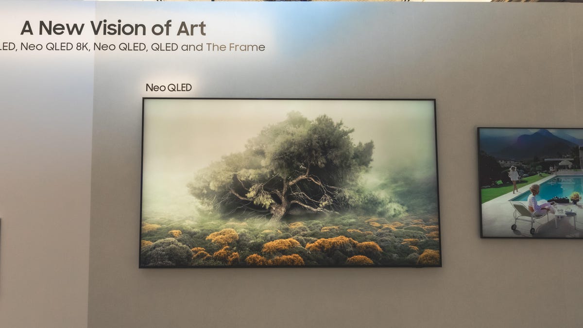 TV hanging on a wall showing a painting of a tree with text 