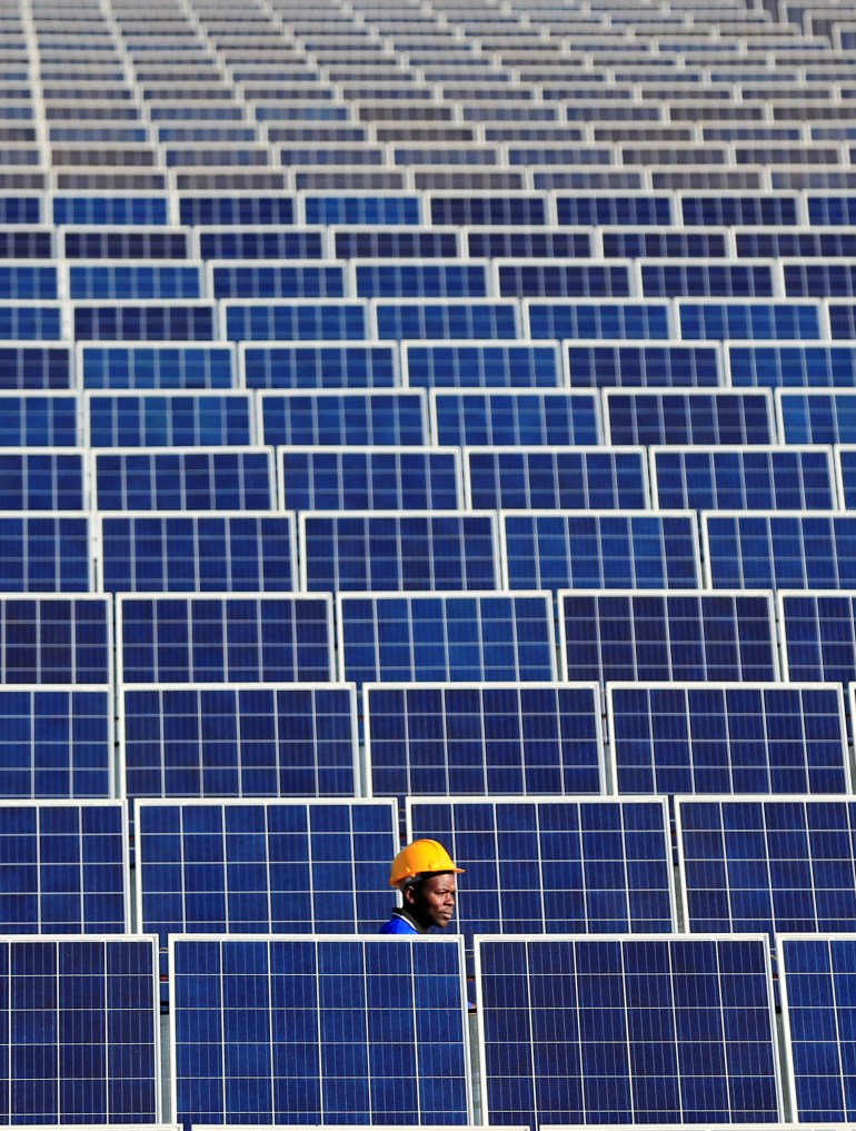 A worker walks between solar panels at Centragrid power plant in Nyabira, Zimbabwe [File: Philimon Bulawayo/Reuters]