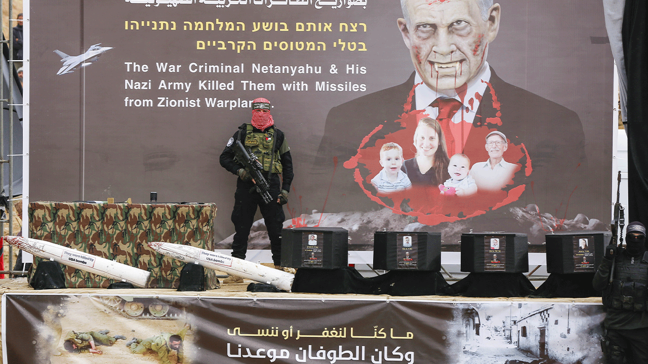 Coffins on stage in Gaza with Hamas member