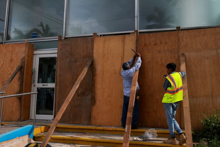 People cover a building with planks of wood as hurricane Erick strengthens off Mexico's Pacific Coast,