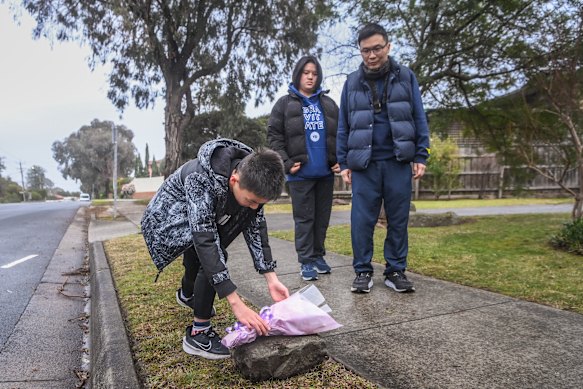 Locals Simon Wong and his children Erica and Torres place a flower tribute at the scene.