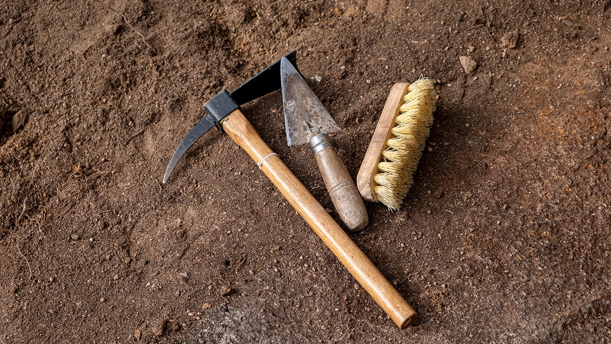 Pickaxe, trowel and brush. Tools in an archaeological excavation