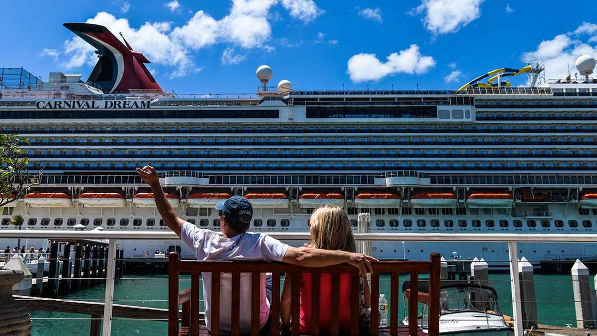 Tourists wave to Carnival Dream cruise ship passengers
