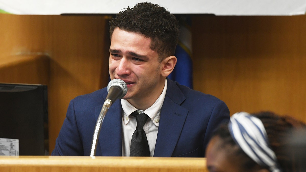 Raul Valle in blue suit and black tie cries while testifying in his own murder trial