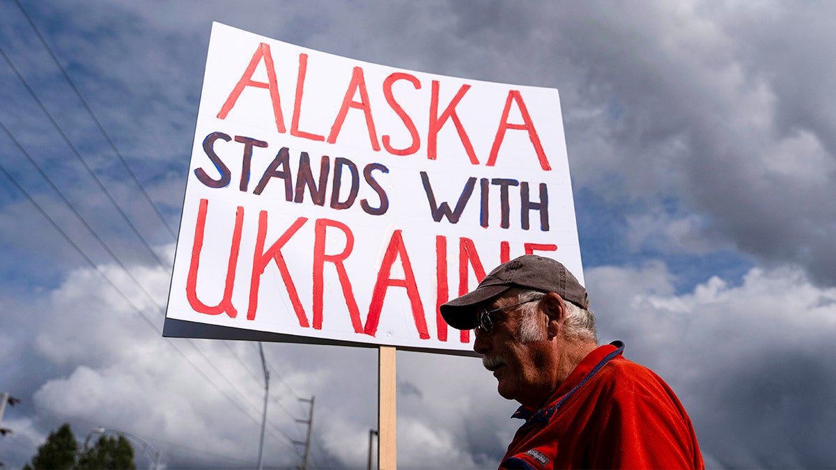 Man holds a sign at a rally the day before Trump-Putin summit in Russia