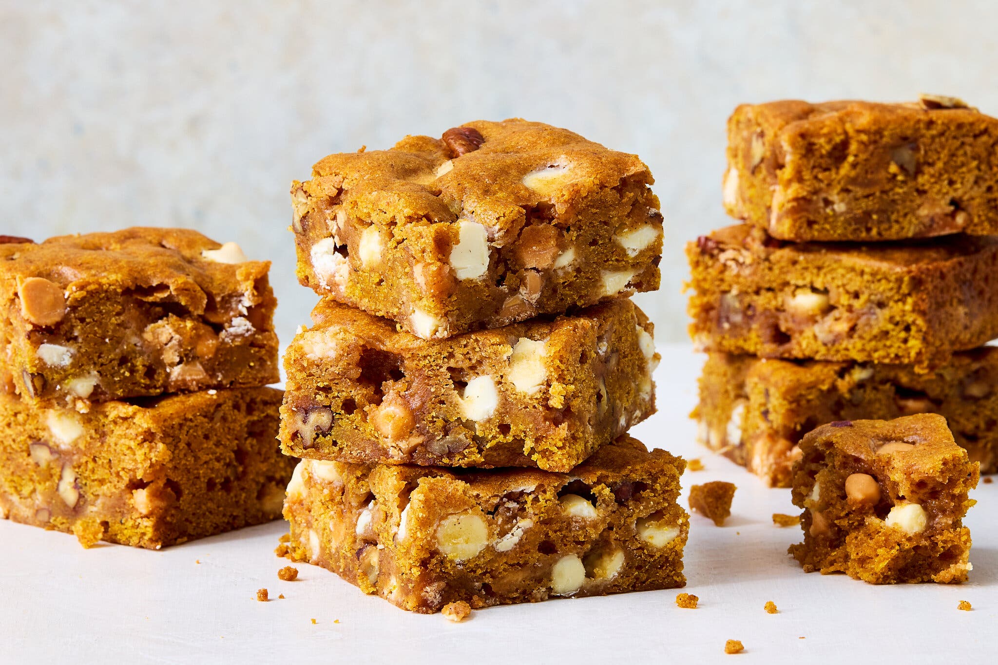 A side image of several stacks of golden blondies studded with white chocolate and butterscotch chips.