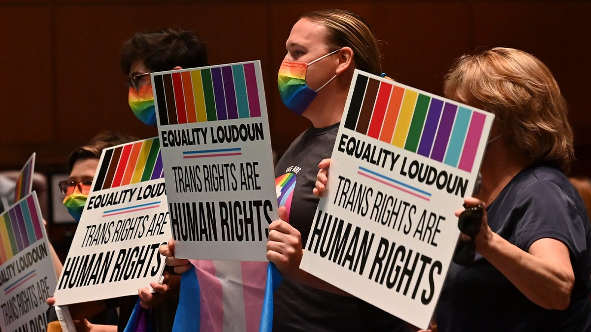 Parents hold signs favoring a rule offering protections for transgender students