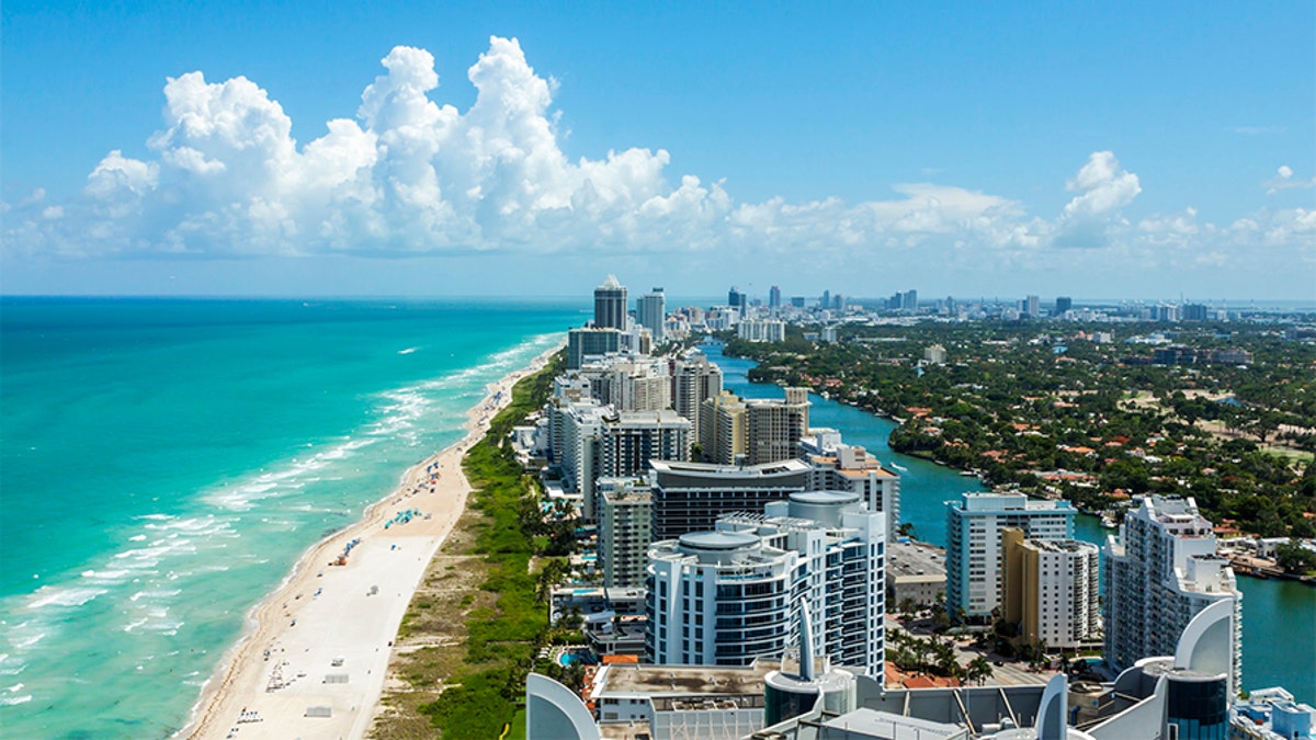 Looking down South Beach in Miami. Full view of the beach on the left and the city on the right. Beautiful blue sky on a clear day.