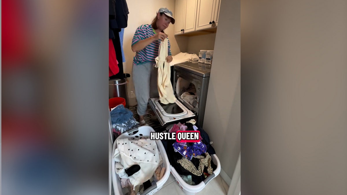 Woman in laundry room folding clothes.