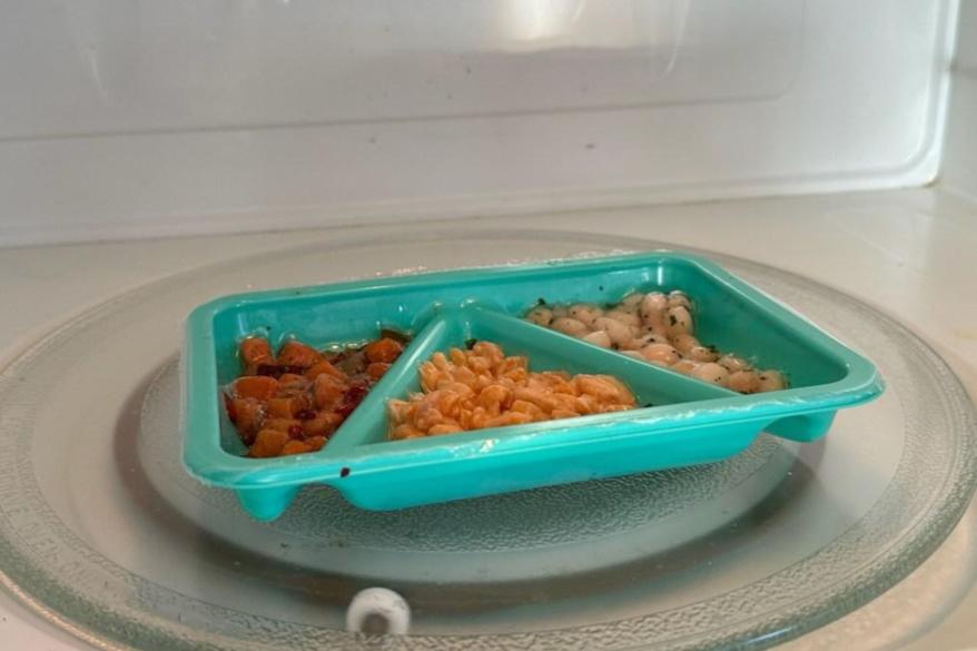 A plate of food for kids in a microwave.