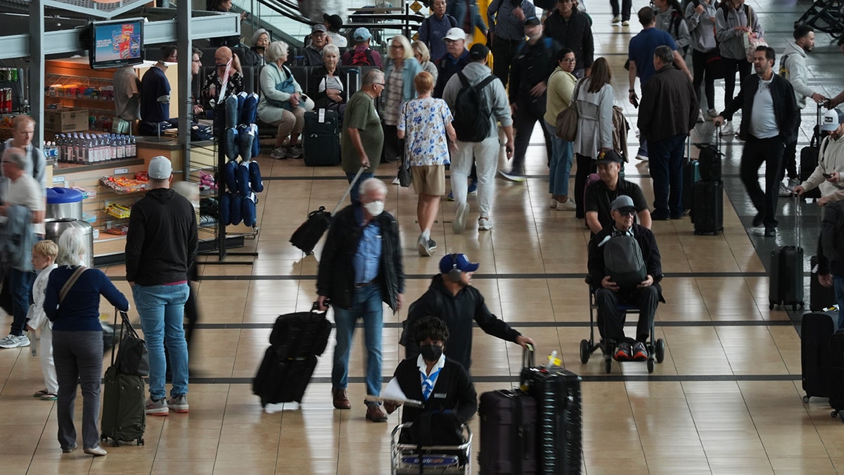 Travelers moving through crowded airport terminal