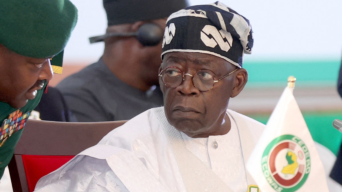 Nigerian President Bola Tinubu speaks with his aide during the 64th ECOWAS Heads of State and Government ordinary session in Abuja on Dec. 10, 2023.