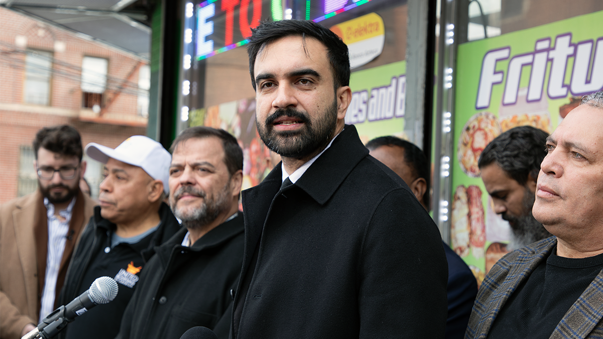 Zohran Mamdani wearing a black coat.