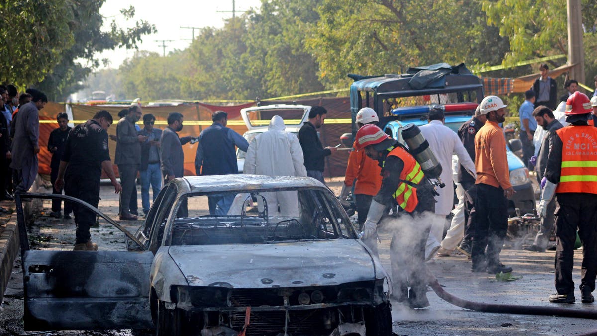 Pakistani police inspect the aftermath of a car bomb.