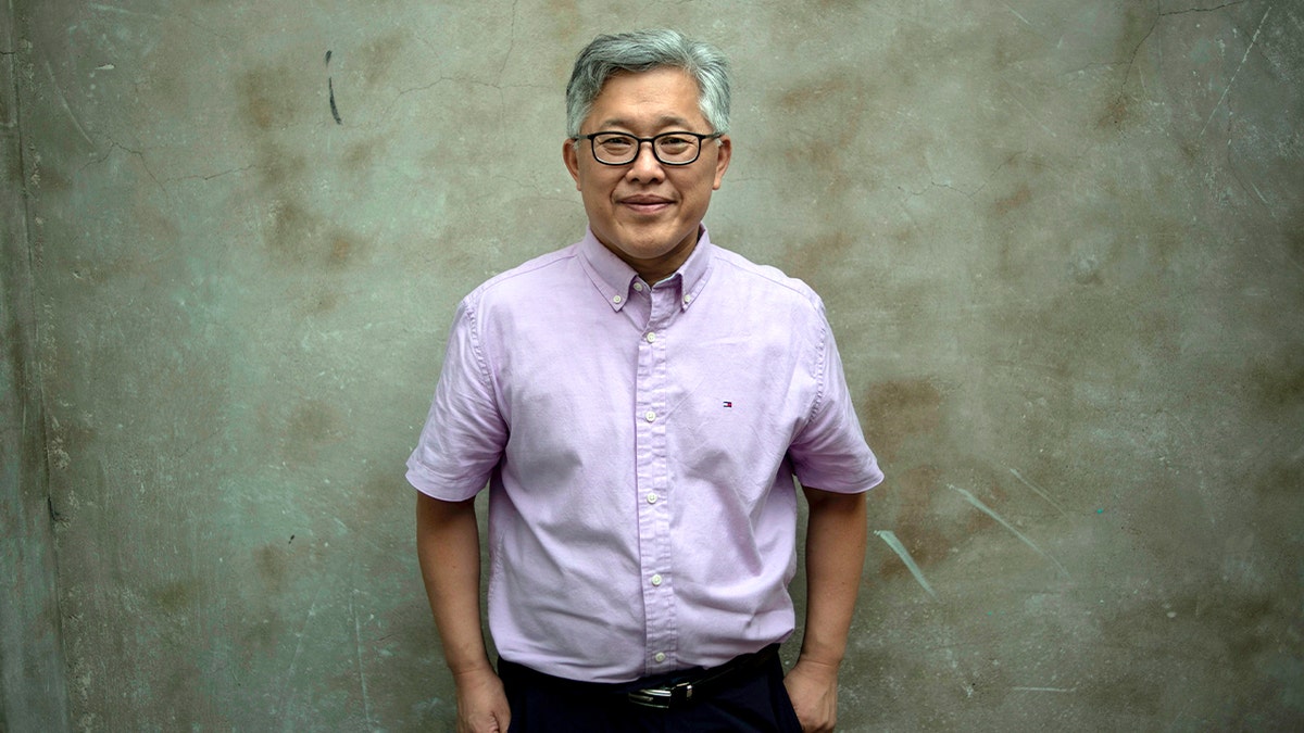A Chinese pastor stands indoors, looking composed after government authorities closed his church.