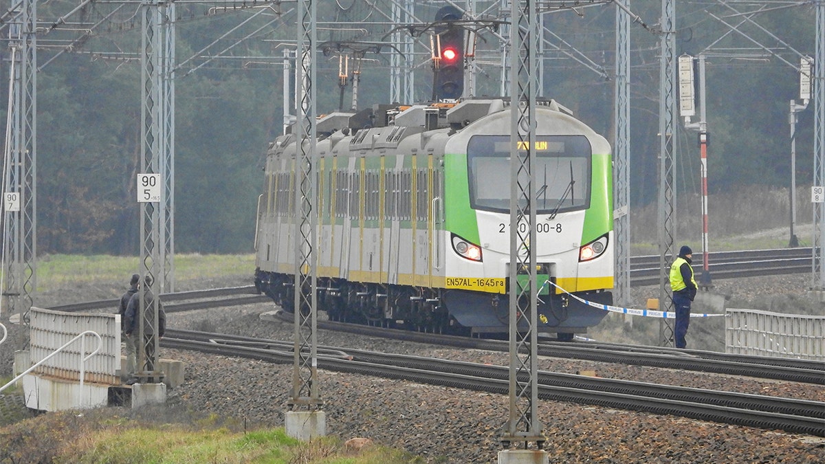 A police officer guards a halted train at an investigation site following an explosion.