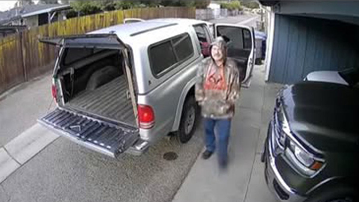 Ron Dailey waring camoflauge sweater near silver car