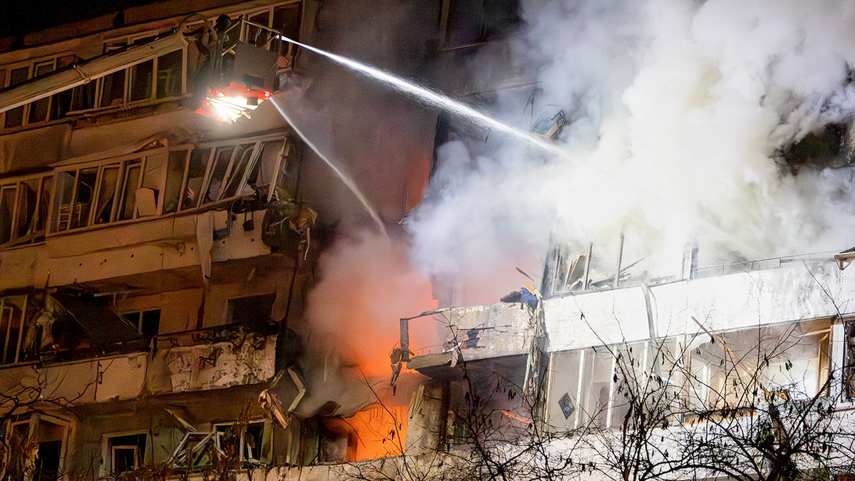 Firefighters spray hose to put out fire in Kyiv, Ukraine, following drone attack by Russia