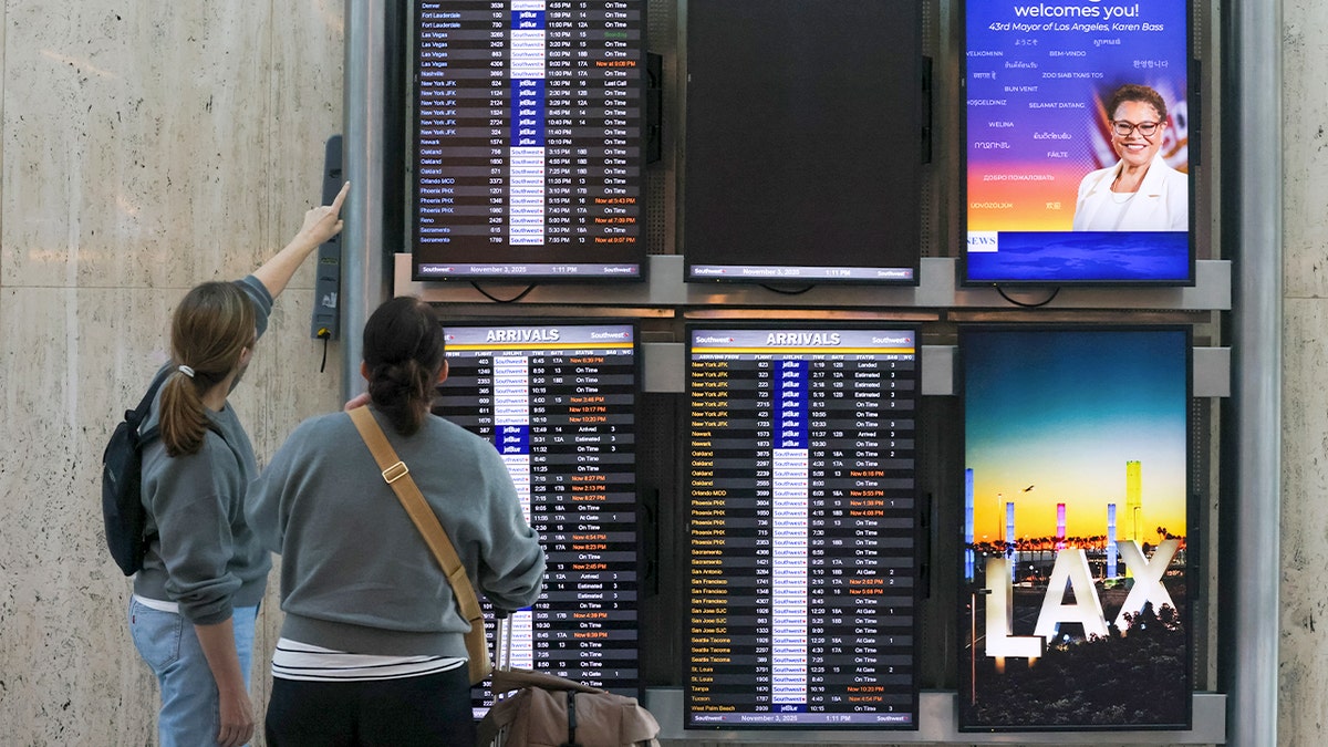 Travelers look at departure times at LAX