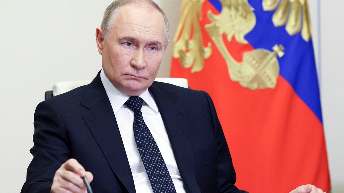 Russian President Vladimir Putin holding pen at desk