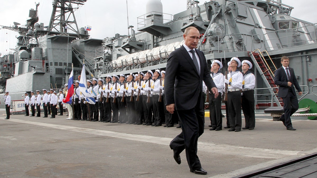 Vladimir Putin tours a naval destroyer during an official visit to a military base.