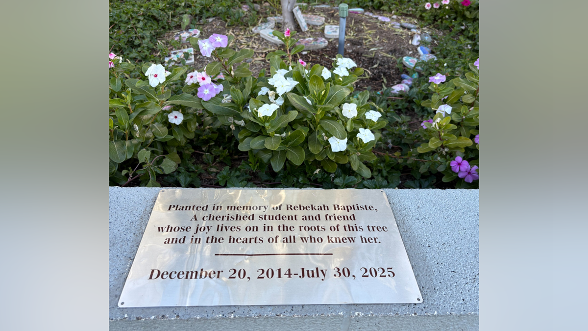 Memorial plaque honoring Rebekah Baptiste sits before flowering plants