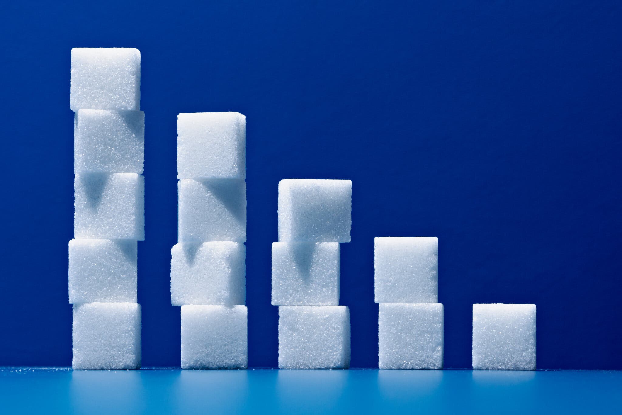 Sugar cubes are stacked in five columns on a blue background.