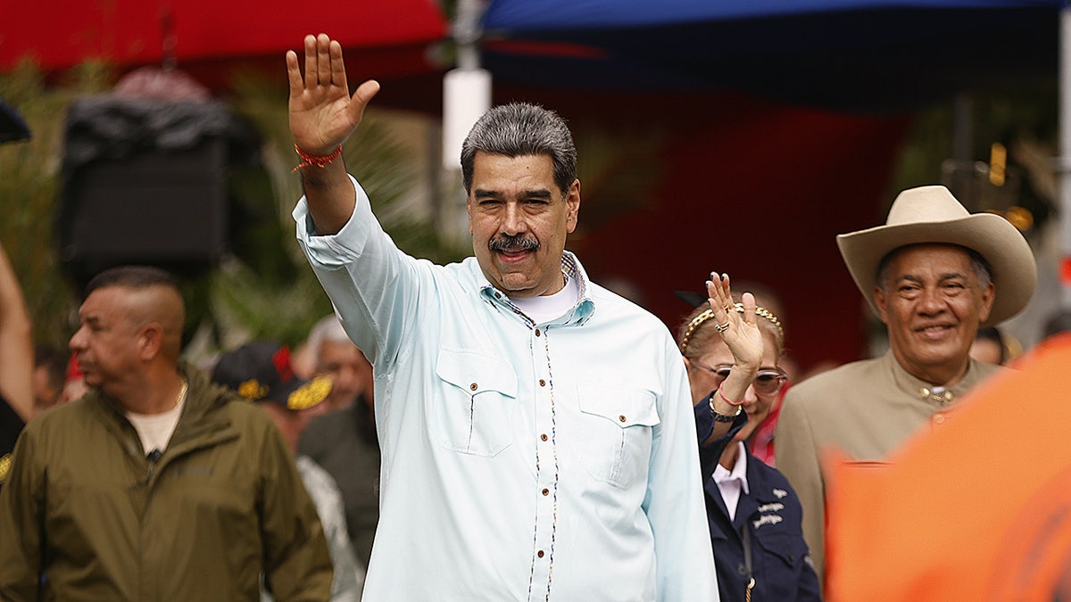 Venezuela President Nicolás Maduro raises hand during rally in Caracas