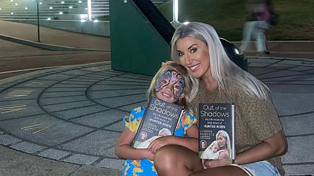 Lunden Roberts and her daughter holding her book