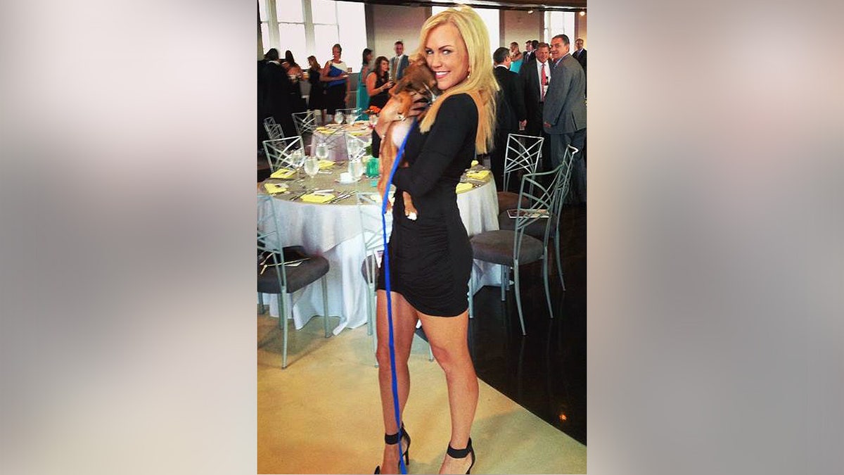 Angelynn "Angie" Mock posing while holding a small dog.