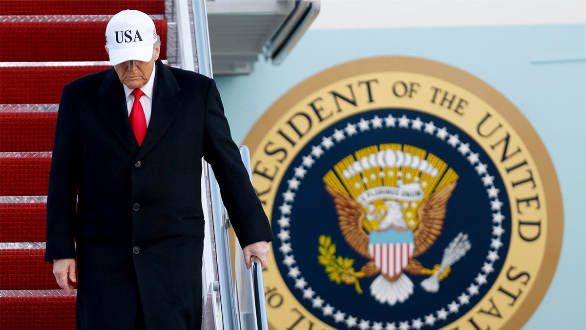 Donald Trump descends the steps of Air Force One after landing at a military base.