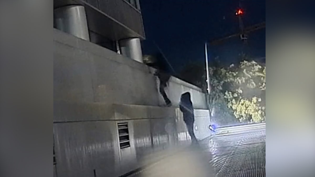 Suspects climb wall outside building at night