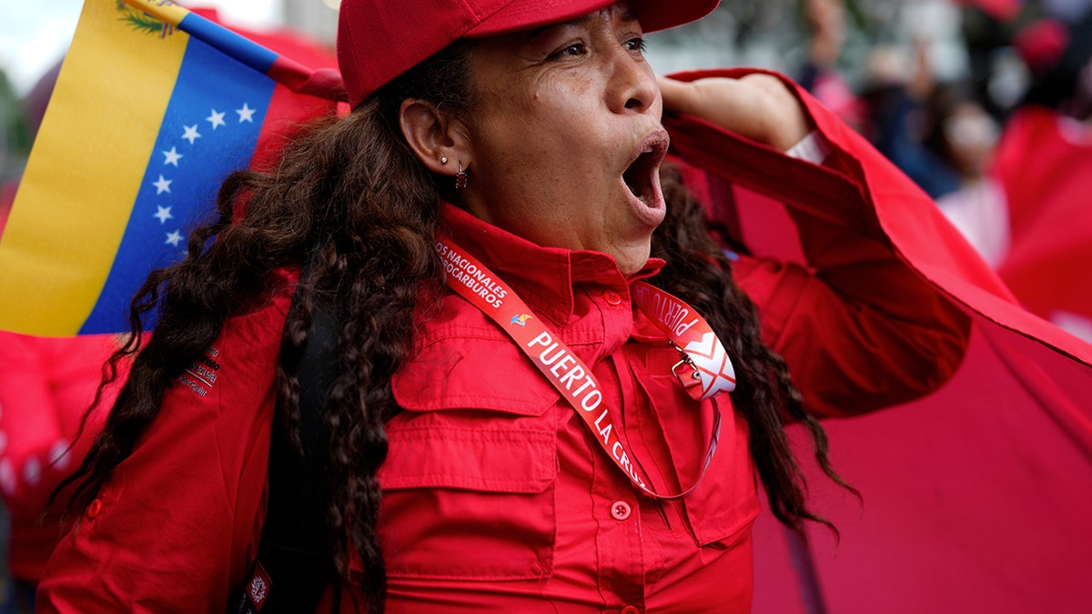 A woman cheers while holding a Venezuelan flag