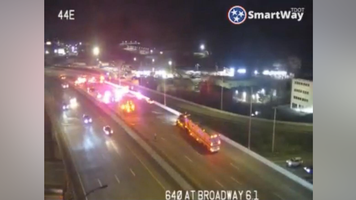 Traffic camera footage shows emergency vehicles responding to a crash on a roadway at night