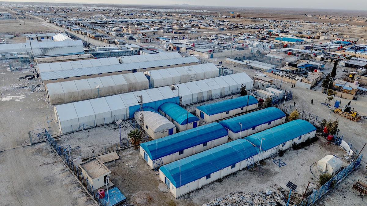 Aerial view of a sprawling tent camp in a remote desert area.