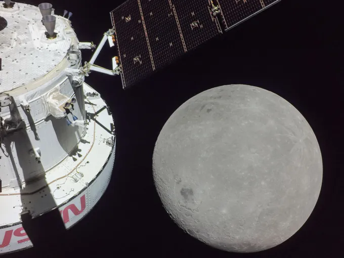 A spacecraft in front of the farside of the moon, which has different features than the side normally facing the Earth