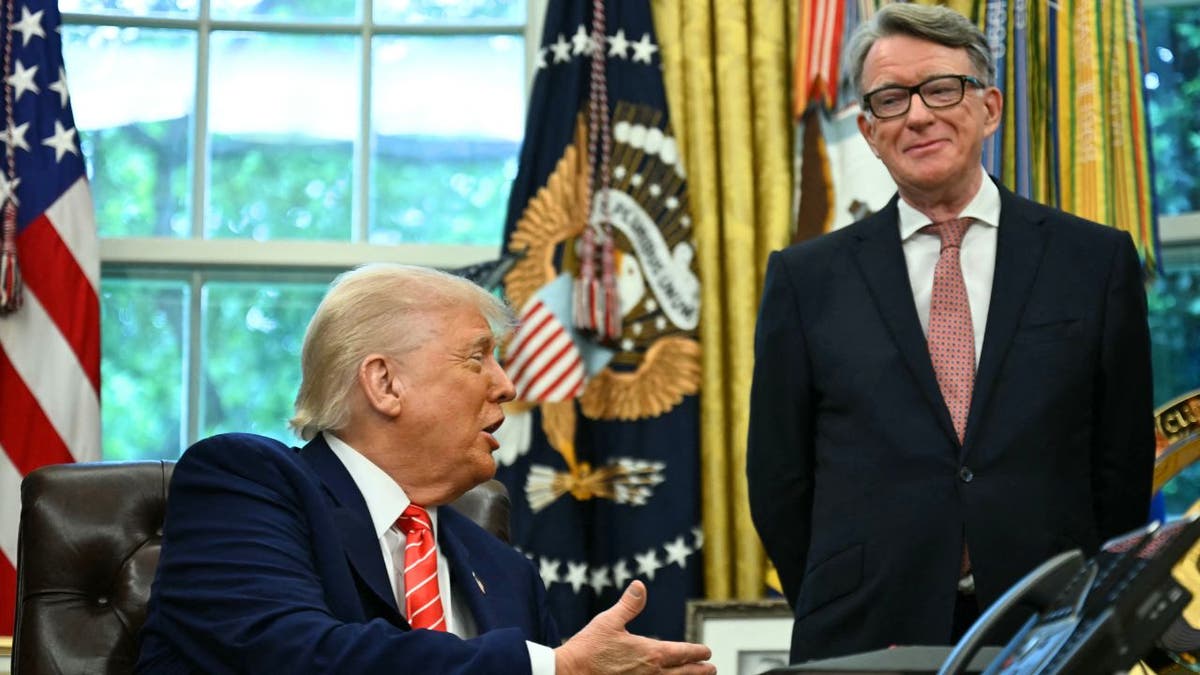Donald Trump speaks at the Resolute Desk as Peter Mandelson stands beside him in the Oval Office
