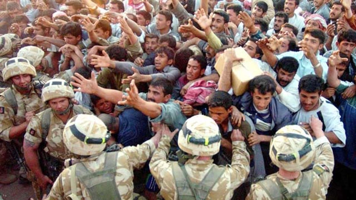 Soldiers of the British Light Infantry distribute aid packages to locals at Zubayr near Basra, southern Iraq, Saturday, March 29, 2003. Significant numbers of Iraqi civilians are trying to leave Basra everyday to get food aid from points around the city before returning. (AP Photo/Brian Roberts)
