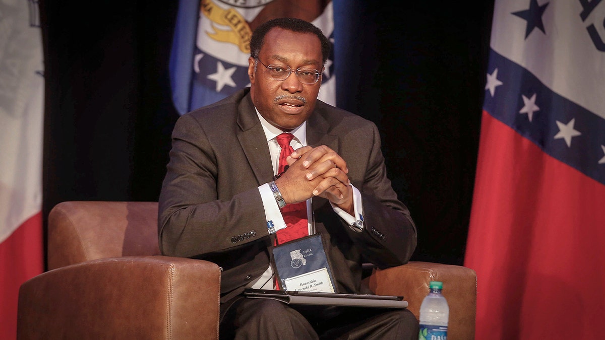 A judge sits on a stage during a legal conference.
