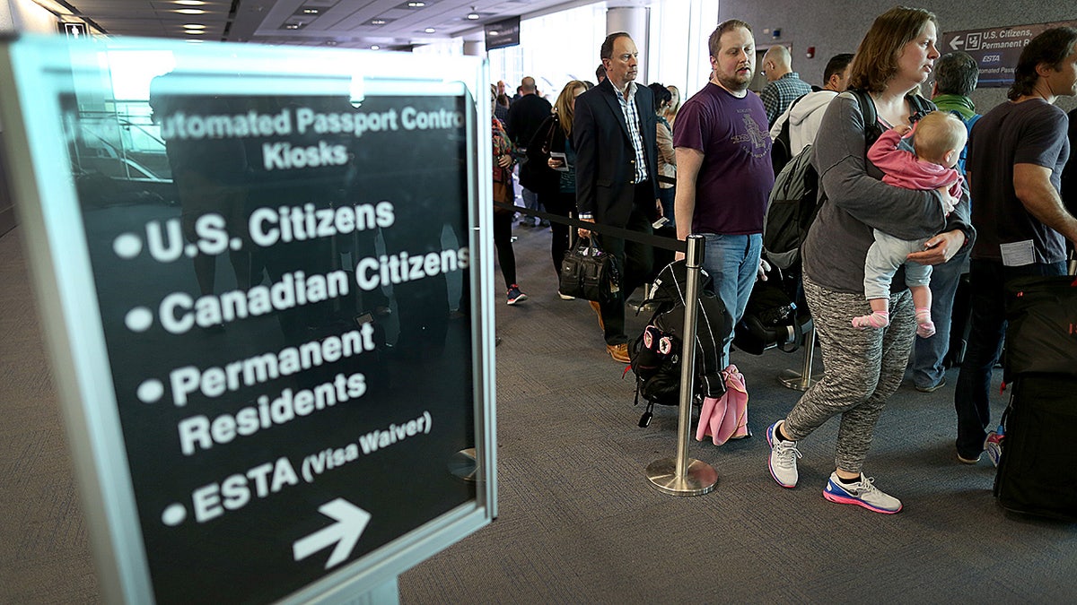 Passengers in Miami stand in line to use Automated Passport Control Kiosks