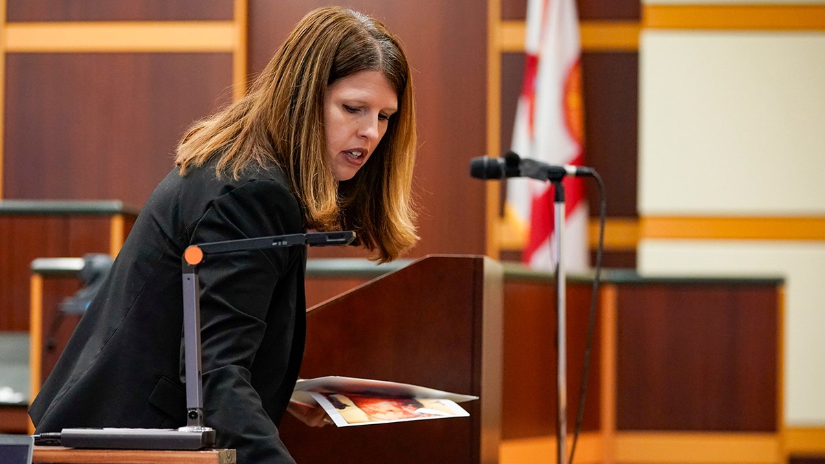 Assistant State Attorney Sara Miller placing photos on a desk in court.