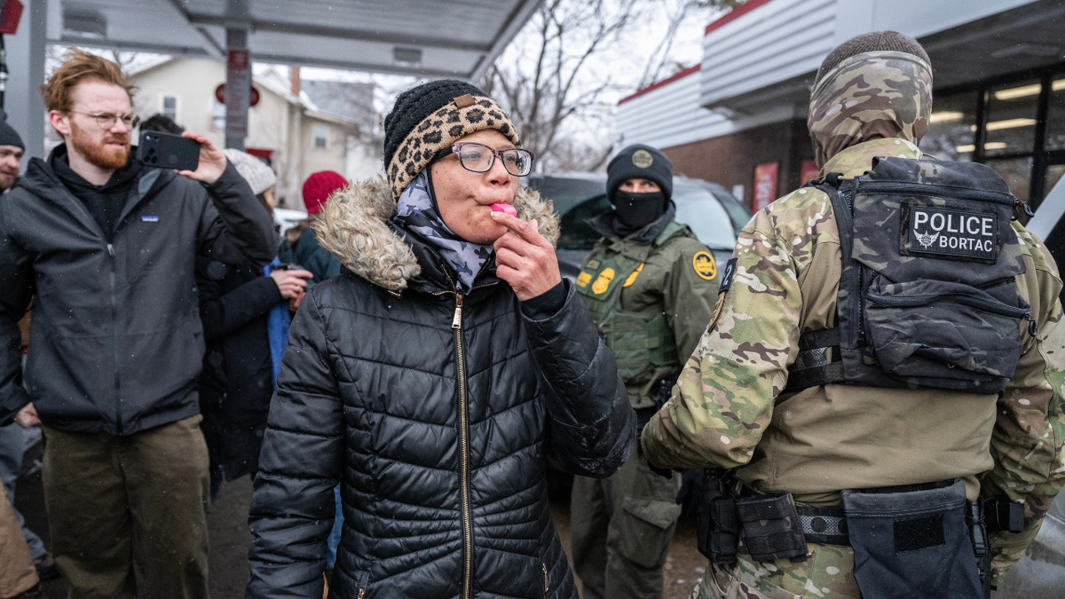 A woman blows a whistle at immigration officials.