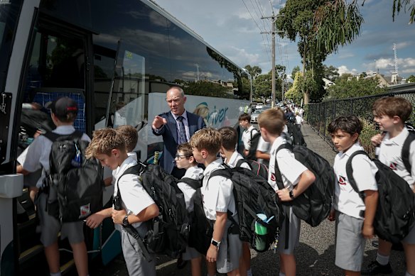 Brett Collison, the director of junior school at Xavier College, with students who travel home on school buses.