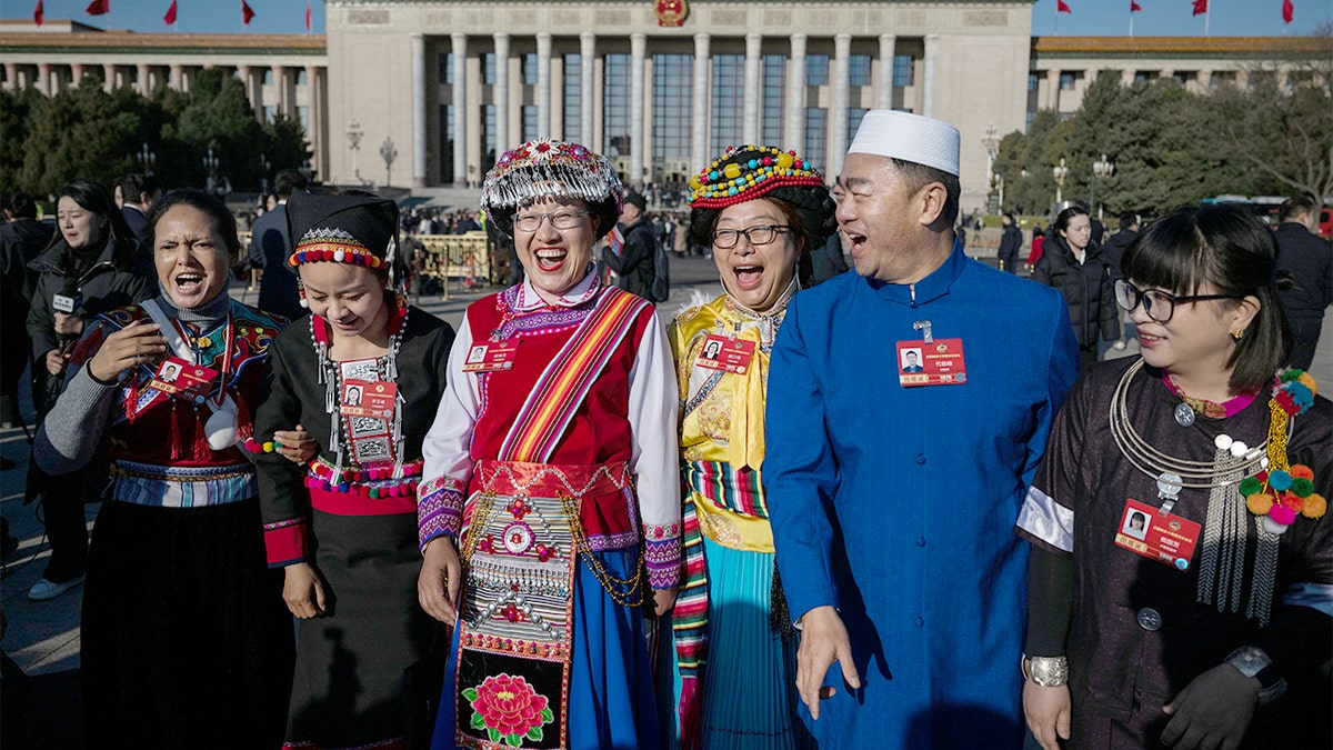 Delegates in traditional attire respond during a high-level political advisory meeting inside Beijing’s Great Hall of the People.