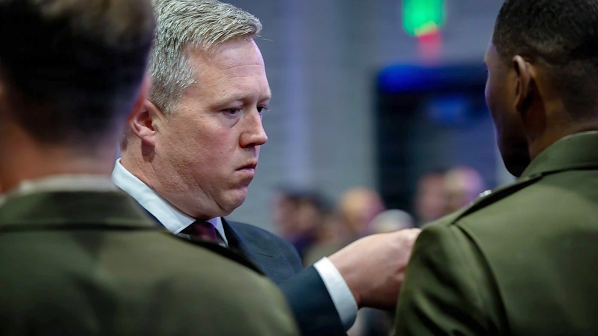 Man in a suit pins a medal on a service member.